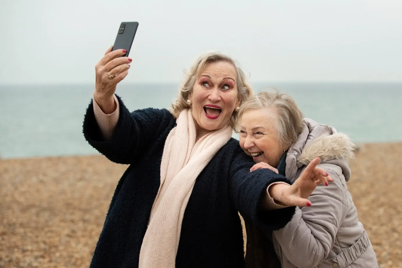 Halbnahe Aufnahme lächelnder Frauen, die am Meer ein Selfie machen.
